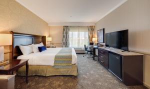 コロナにあるAyres Hotel Corona Eastのベッド1台、薄型テレビが備わるホテルルームです。