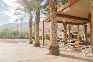 un patio con palmeras, mesas y sillas en Ace Hotel and Swim Club Palm Springs, en Palm Springs