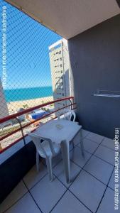 een tafel en stoel op een balkon met uitzicht op het strand bij Porto de Iracema Vista Mar in Fortaleza
