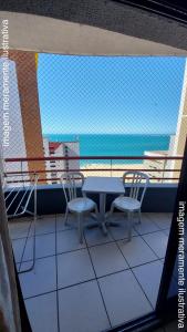een tafel en stoelen op een balkon met uitzicht op de oceaan bij Porto de Iracema Vista Mar in Fortaleza