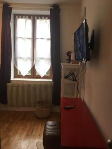 een woonkamer met een televisie en een raam bij L auberge du lion d or in Nanteuil-sur-Marne