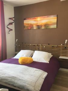 a bed with a yellow pillow sitting on top of it at L auberge du lion d or in Nanteuil-sur-Marne