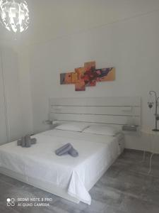 una camera da letto con un letto bianco con un dipinto sul muro di Pierpa's House o Casa Pierpa a Catania