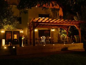a pergola with chairs and tables in a yard at night at Hotel Les Terrasses in Annecy