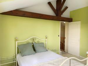 a bedroom with a white bed with green walls at Villas de la Plaine in Calès