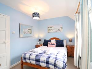 ein Schlafzimmer mit einem Bett mit blauen Wänden in der Unterkunft Guinea Cottage in Weymouth