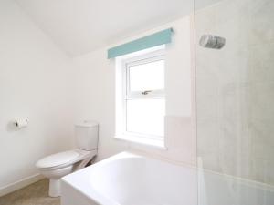 ein weißes Bad mit einem WC und einem Fenster in der Unterkunft Guinea Cottage in Weymouth + 22 Fotos