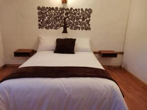 瓜斯卡的住宿－Hotel Mi Villa，卧室配有一张床铺,墙上挂着一棵树