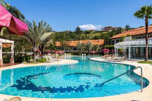 uma grande piscina com cadeiras e guarda-sóis num resort em Villa di Mantova Resort Hotel em Águas de Lindoia