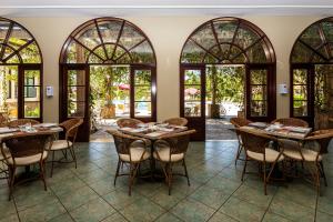 una sala da pranzo con tavoli, sedie e finestre di Villa di Mantova Resort Hotel ad Águas de Lindóia