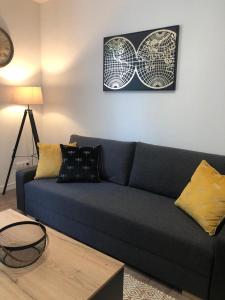 een woonkamer met een blauwe bank en een tafel bij Paisible logement à Brive proche centre-ville et campagne avec Wifi Netflix et Parking privé in Brive-la-Gaillarde