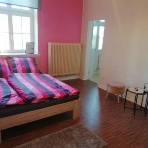 1 dormitorio con 1 cama con pared de color rosa y mesa en Gästezimmer Vermietung Reinstorf, en Reinstorf