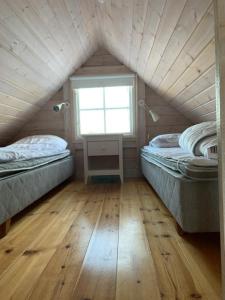 a attic room with two beds and a window at Kappelshamns Veranda och Fritidsboende in Kappelshamn