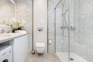 a bathroom with a shower with a toilet and a sink at Baltini Premium Apartament Kasprowicza 20 A-B z basenem, saunami i jacuzzi in Kołobrzeg