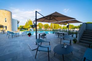 a patio with tables and chairs and an umbrella at Best Western Plus Sabaudia Hotel in Sabaudia