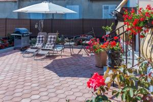 eine Terrasse mit Stühlen, einem Sonnenschirm und Blumen in der Unterkunft Apartments & Rooms Hosana in Zadar