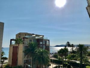 a building with palm trees in front of a body of water at Ca_LaGrava in Jávea