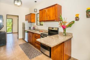 a kitchen with wooden cabinets and a counter top at Villa Iguana - Great place & privacy with Jacuzzi & WiFi in Quepos