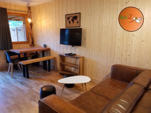 a living room with a couch and a table and a tv at Rev2 Montagne in La Bresse