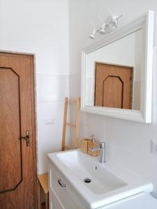 een badkamer met een witte wastafel en een spiegel bij Casa Teresa in Castellaneta