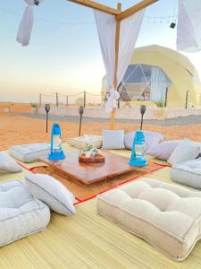 a group of pillows on a table in the desert at Starry Domes Desert Camp in Badīyah