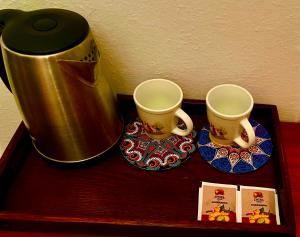 two cups on a wooden table next to a coffee pot at Convini Bed & Bathroom Homestay in Prishtinë