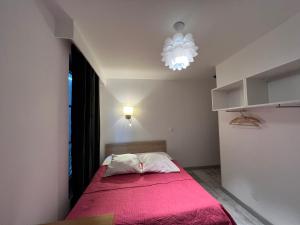 a bedroom with a bed with a pink blanket at Hôtel Belle Fontainebleau in Fontainebleau