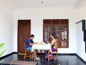 a man and woman sitting at a table eating food at Anara Villa in Unawatuna