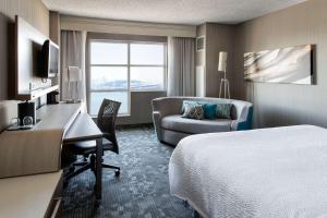 a hotel room with a bed and a desk and a couch at Sonesta Emeryville San Francisco Bay Bridge in Emeryville