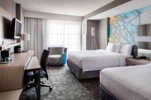 a hotel room with two beds and a desk at Sonesta Emeryville San Francisco Bay Bridge in Emeryville