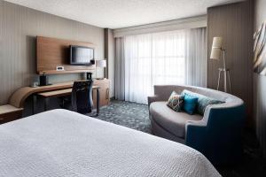 a hotel room with a bed and a chair and a desk at Sonesta Emeryville San Francisco Bay Bridge in Emeryville