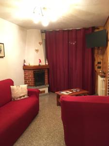 ein Wohnzimmer mit einem roten Sofa und einem Kamin in der Unterkunft Appartamento Castellaccio in Ponte di Legno