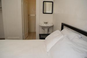 um quarto com uma cama branca e um lavatório em Hotel Ikon em São Francisco