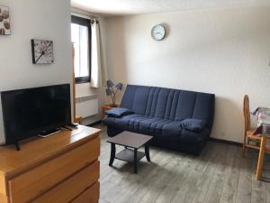 sala de estar con sofá azul y TV en Les Cimes en Samoëns