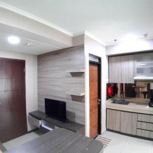 una cocina con pared y TV. en High Livin Apartment Pasteur en Bandung