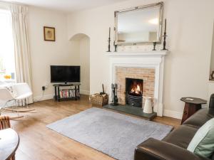 a living room with a fireplace and a mirror at 1 Blinkbonny Cottages in Saint Boswells