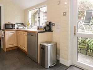 a kitchen with a sink and a trash can at 1 Blinkbonny Cottages in Saint Boswells