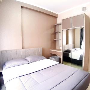 1 dormitorio con 1 cama blanca grande y espejo en High Livin Apartment Pasteur en Bandung