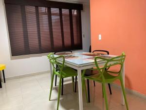 mesa de comedor con sillas verdes y ventana en Apartamentos Laureles de la 70, en Medellín