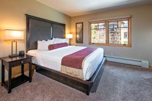 a bedroom with a large bed and two windows at Grand Timber Lodge in Breckenridge