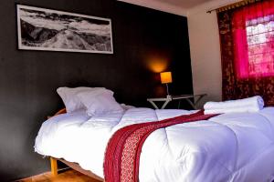 a bedroom with two beds with white sheets and a red window at The Willow B&B in Urubamba