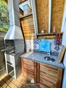 a kitchen with a stove and a sink at VILLAM AREIA FOFA in Bombinhas