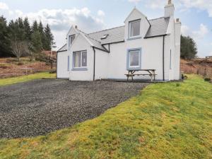 a white house with a picnic bench in front of it at Bayview House in Fiskavaig