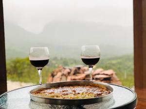 dos copas de vino tinto al lado de un plato de comida en Casa dos Sonhos en Ibicoara