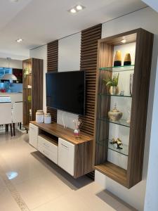 una sala de estar con TV en un centro de entretenimiento de madera en Apartamento com 3 dormitórios en Balneário Camboriú