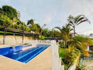 a swimming pool with a white fence and palm trees at Finca Villa Maju K24 Vista naturaleza clima delicioso A 30 min Cali in Papagalleros