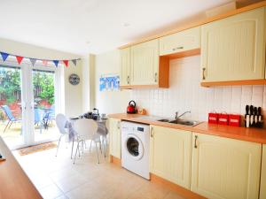 eine Küche mit weißen Schränken und einer Waschmaschine in der Unterkunft Mariner's Rest in Weymouth