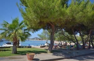 a park with trees and people sitting on the beach at Apartment Zdravko in Srima
