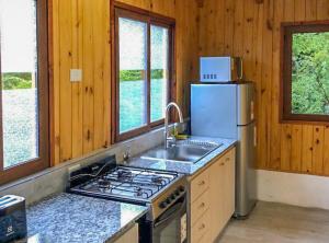 a kitchen with a stove and a sink and a refrigerator at Cabañas Viajeros Patagónicos Moquehue in Moquehue +33 photos