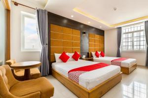 1 dormitorio con 2 camas con almohadas rojas y silla en khách sạn Thiên Cung en Ho Chi Minh